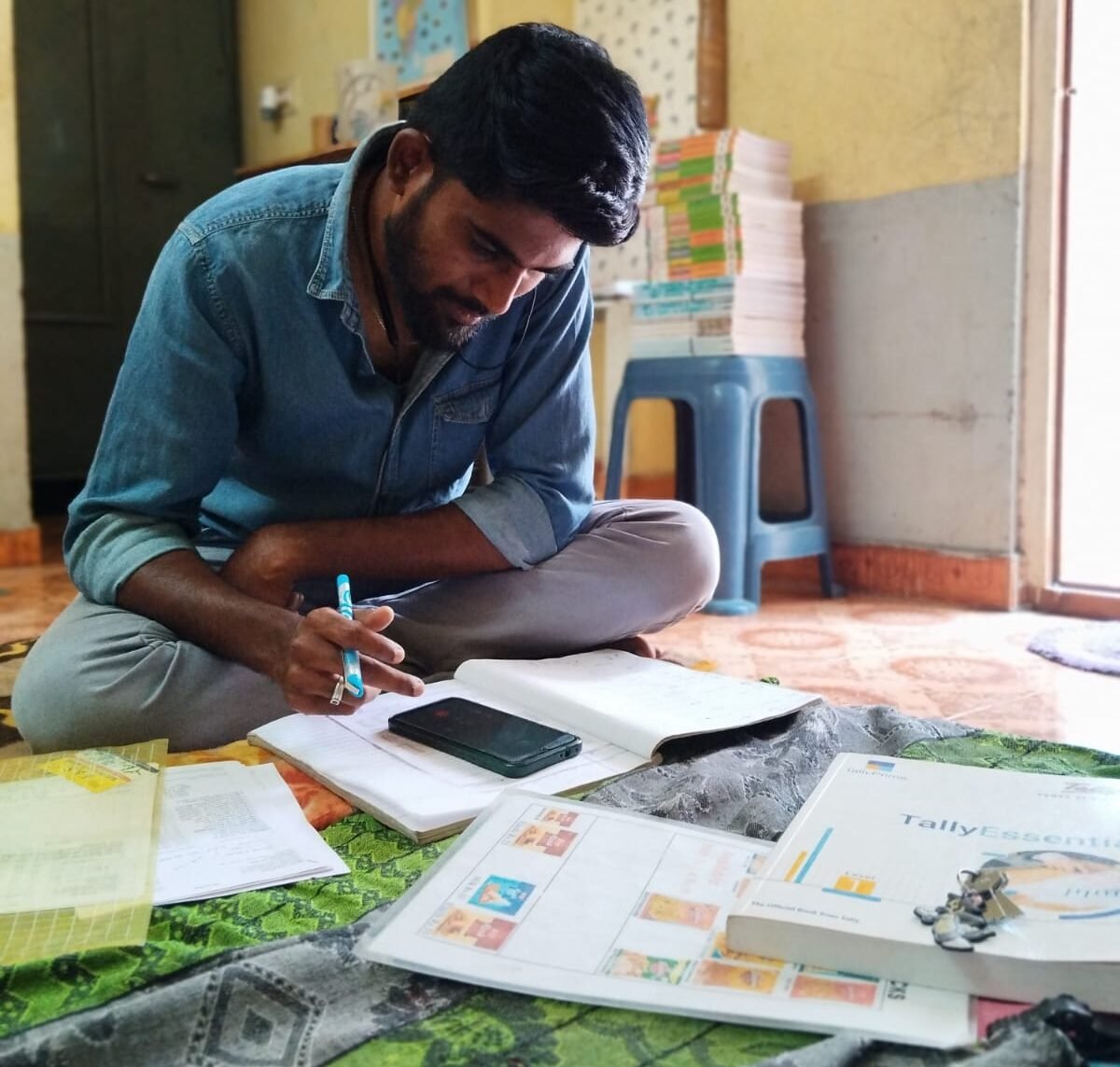 Farook, Suresh analyzing B2B logistics data, stock sheets, and Tally inventory books for Mani Traders startup in Coimbatore.